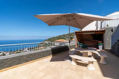 a patio with a table and an umbrella at Villa Abreu - A Wonderful Ocean View in Calheta