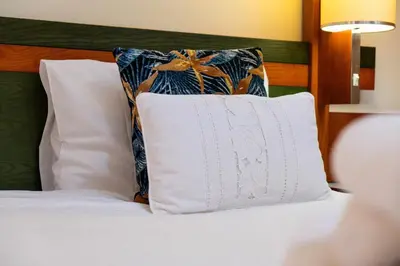a bed with a white pillow and two pillows at Garajau Terrace - Amazing Views of Garajau Town in Garajau