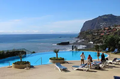 people walking around a swimming pool next to the ocean at Atlantic Ocean View Apartment in Funchal