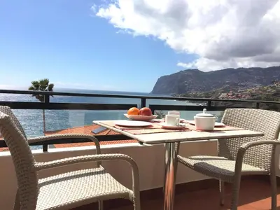 a table and chairs on a balcony with a view of the ocean at Ocean Cliffs Apartments in Funchal