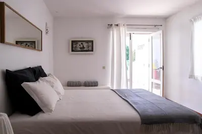 a white bedroom with a large bed with a window at Beach House at Praia da Luz in Luz