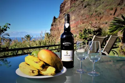 a bottle of wine and a plate of fruit on a table at Sunset Sea Breeze in Madalena do Mar