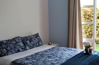 a bedroom with a bed with a blue blanket and a window at Sunset Sea Breeze in Madalena do Mar
