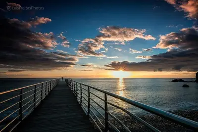 a wooden boardwalk leading into the ocean at sunset at Sunset Sea Breeze in Madalena do Mar