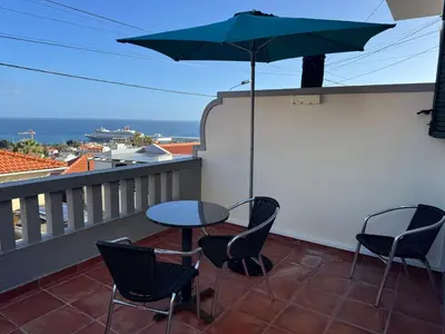 a table and chairs on a balcony with an umbrella at Casa das Cruzes in Funchal