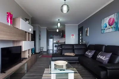 a living room with a black couch and a tv at Casa do Louro in Arco da Calheta