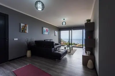 a living room with a couch and a chair and a balcony at Casa do Louro in Arco da Calheta