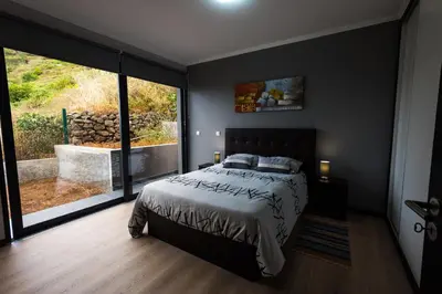 a bedroom with a bed and a large window at Casa do Louro in Arco da Calheta