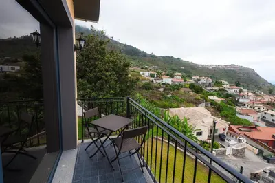 a balcony with a table and chairs on a hill at Casa do Louro in Arco da Calheta