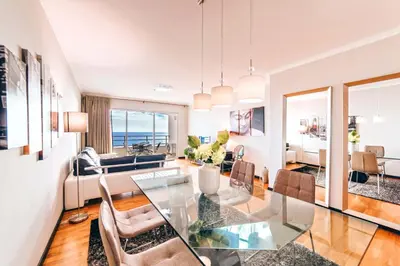 a dining room and living room with a glass table and chairs at Oceanside Terrace Apartment by Holiday Rental Madeira in Funchal