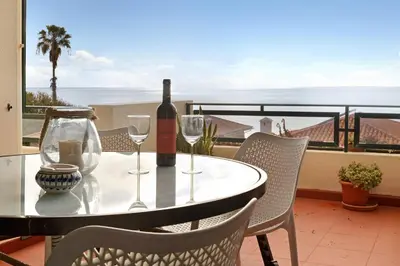 a table with a bottle of wine and glasses on a balcony at Luzias Apartment in Funchal