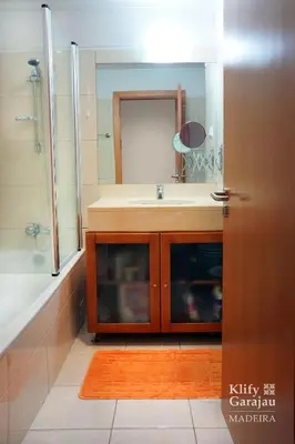 a bathroom with a sink and a shower and a mirror at Klify Garajau in Caniço