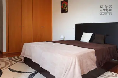 a bedroom with a large bed with a brown blanket at Klify Garajau in Caniço