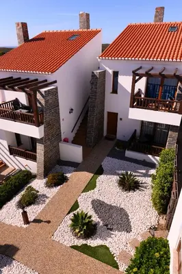 a bedroom with a white bed with a floral bedspread at Falésias da Arrifana in Praia da Arrifana