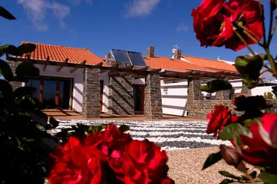 a house with red flowers in front of it at Falésias da Arrifana in Praia da Arrifana