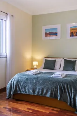 a bedroom with a large bed with a blue blanket at Sea View Apartment in Santa Cruz