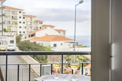 two glasses of white wine on a table on a balcony at Sea View Apartment in Santa Cruz