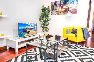 a living room with a tv and a yellow couch at Enredos Serenos Apartment in Funchal