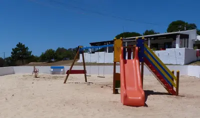 a playground in the sand in front of a building at Parque de Campismo Orbitur Sagres in Sagres