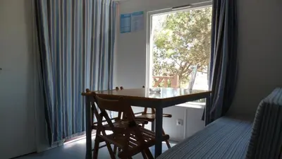 a table and chairs in a room with a window at Parque de Campismo Orbitur Sagres in Sagres