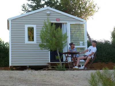 a man and woman sitting in chairs in front of a shed at Parque de Campismo Orbitur Sagres in Sagres