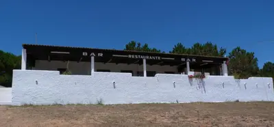 a building with a white wall in front of it at Parque de Campismo Orbitur Sagres in Sagres