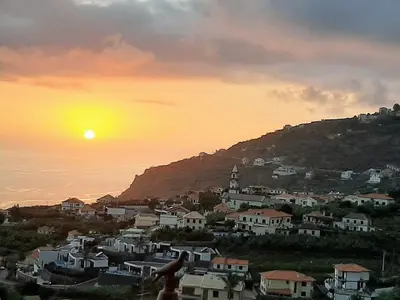 a view of a town with the sun setting on a hill at Casa Ventura in Arco da Calheta