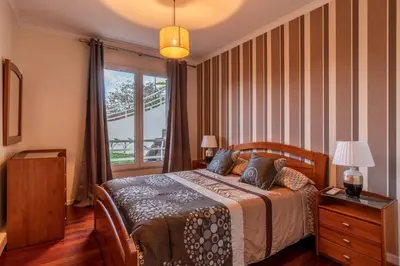 a bedroom with a bed and a large window at Casa Branca with garden by Holiday Rental Madeira in Funchal