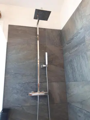 a shower with a light on the top of a shower at Au petit Madère in Prazeres