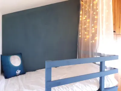 a bedroom with a blue wall with a bunk bed with lights at Au petit Madère in Prazeres
