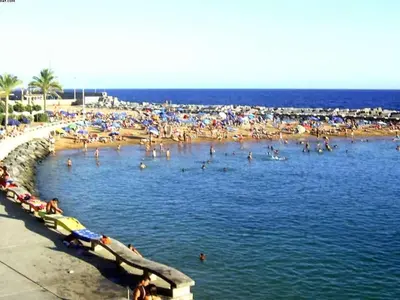 a beach with a bunch of people in the water at Apartamento do Sol in Arco da Calheta