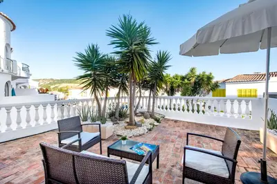a patio with chairs and a table and palm trees at Villa Waterside in Luz