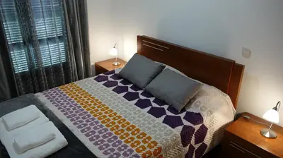 a bedroom with a bed with a colorful blanket and two lamps at Jardins Piornais Funchal Apartment in Funchal