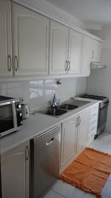 a kitchen with white cabinets and a sink and a microwave at Jardins Piornais Funchal Apartment in Funchal