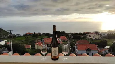 a bottle of wine and two glasses on a ledge at Vista Romantica Madeira in Arco da Calheta