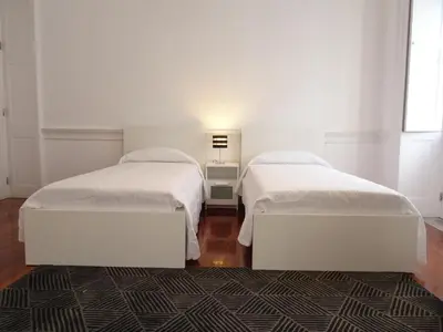 two beds in a room with white walls and a rug at Museum House in Funchal