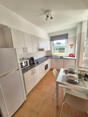 a kitchen with a table and a white refrigerator at Cantinho do Porto Santo in Porto Santo