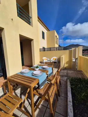 a patio with wooden tables and chairs and a building at Cantinho do Porto Santo in Porto Santo