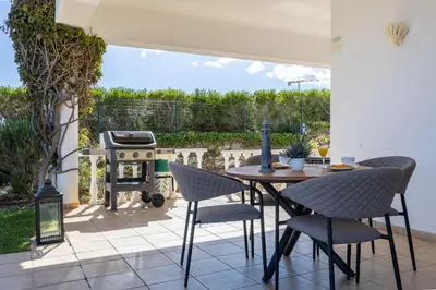 a patio with a table and chairs and a grill at Villa Zinha in Luz