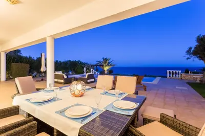 a dining table on a patio with a view of the ocean at Villa Zinha in Luz