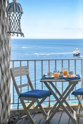 a table and chairs on a balcony with the ocean at Apartamentos do Mar in Funchal