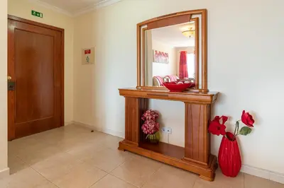 a hallway with a mirror and a vase with flowers at Apartamento Rodrigues in Funchal
