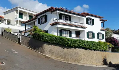 a white house with black windows on a street at Charming Apartments in Funchal - São Gonçalo in Funchal