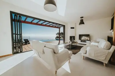 a living room with white furniture and a view of the ocean at Ocean View Villa in Funchal