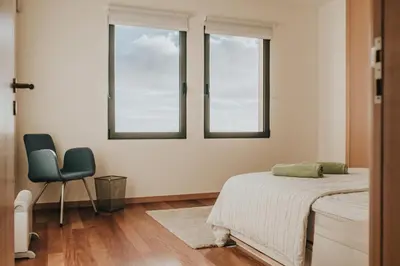 a bedroom with a bed and a chair and two windows at Ocean View Villa in Funchal