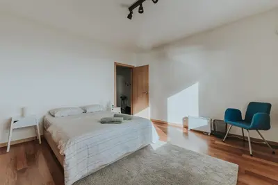a white bedroom with a bed and two blue chairs at Ocean View Villa in Funchal