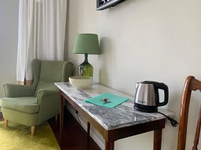 a desk with a green chair and a lamp and a table at Belvedere Boutique - Adults only in Funchal