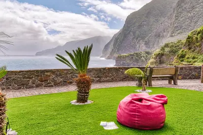 a pink bag sitting on the grass near the ocean at Seixal Sunny Villa A & B by Amazing Madeira in Seixal
