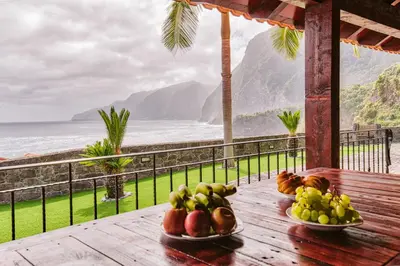 two bowls of fruit on a wooden table with a view of the ocean at Seixal Sunny Villa A & B by Amazing Madeira in Seixal