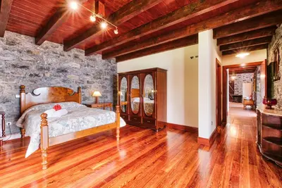 a bedroom with a bed and a stone wall at Seixal Sunny Villa A & B by Amazing Madeira in Seixal